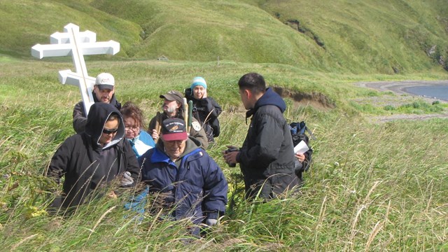 People in a grassy field with a Russian cross